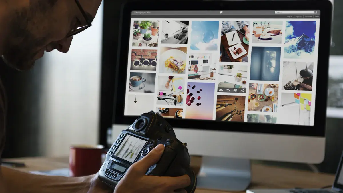 Photographer looking at DSLR camera with monitor and web portfolio in the background